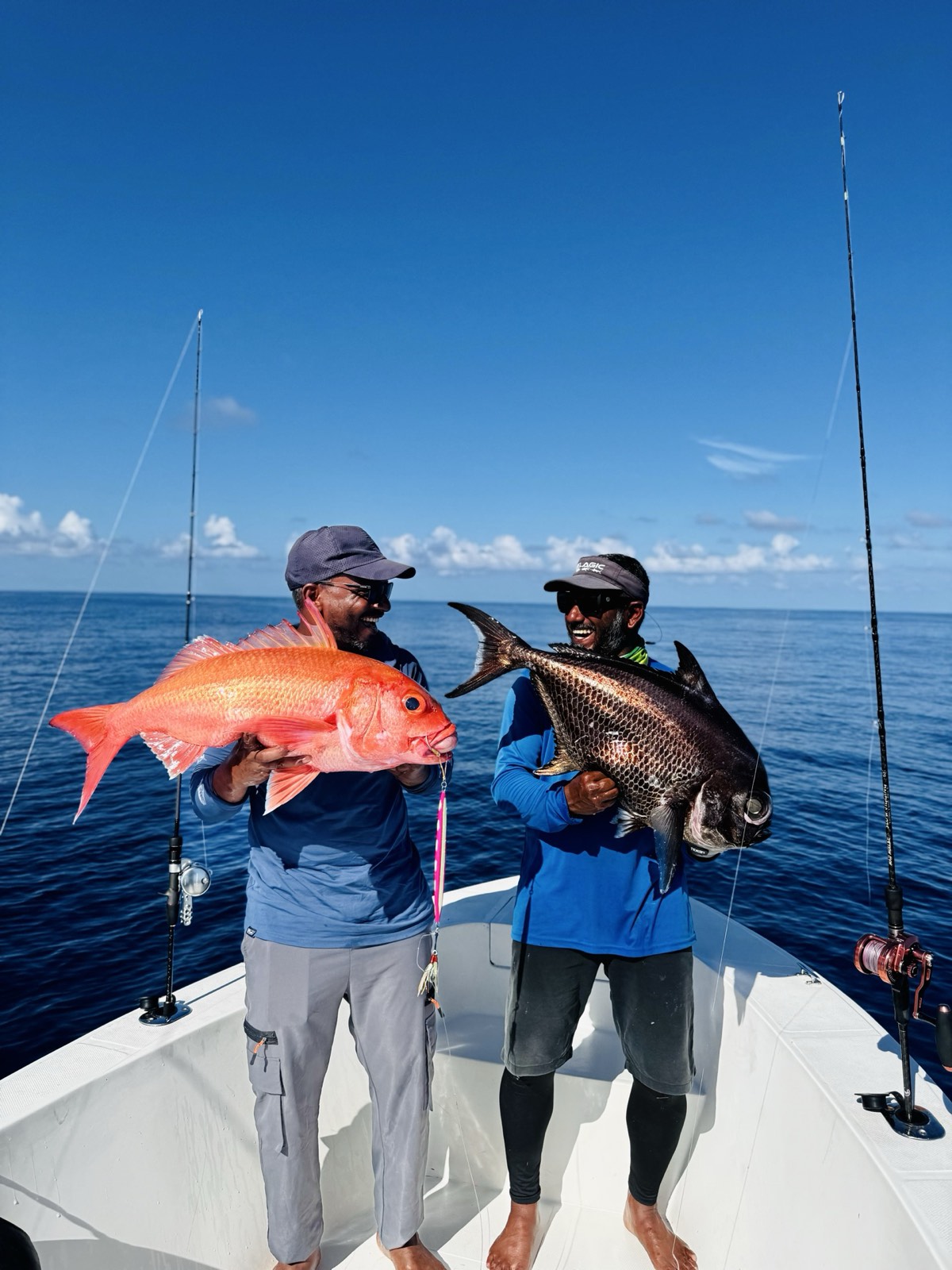 Two anglers on our boat holding a red snapper and a trevally